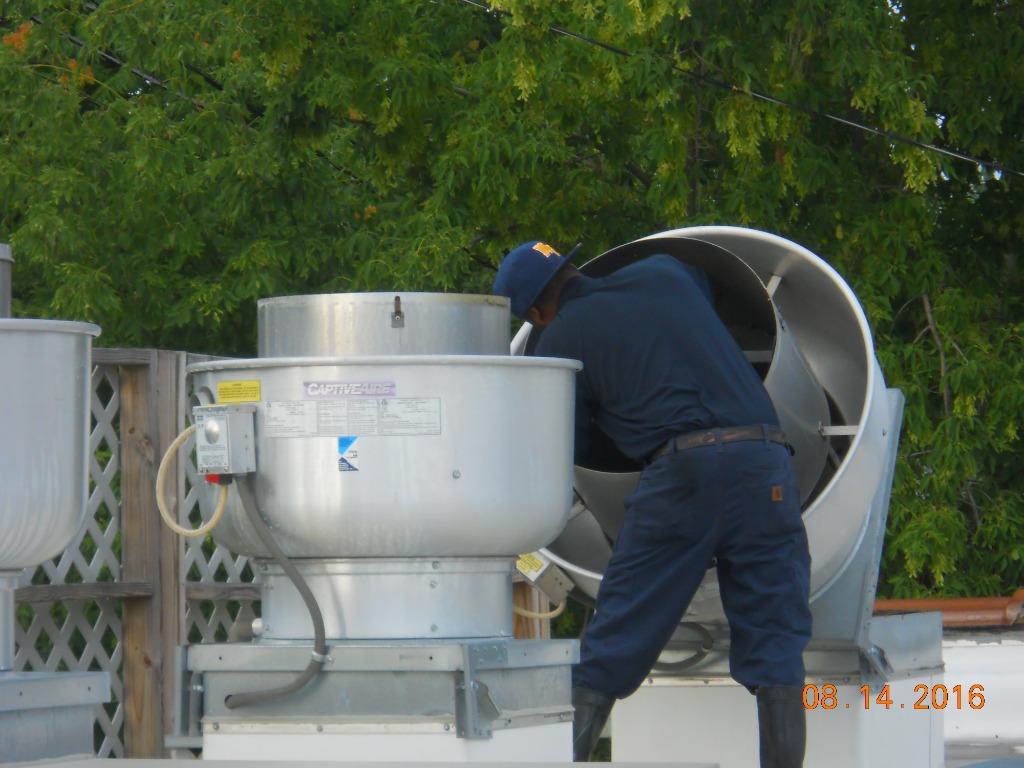 ISC technician performing rooftop exhaust fan cleaning and maintenance