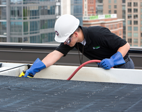 Technician cleaning commercial kitchen hood filters on rooftop